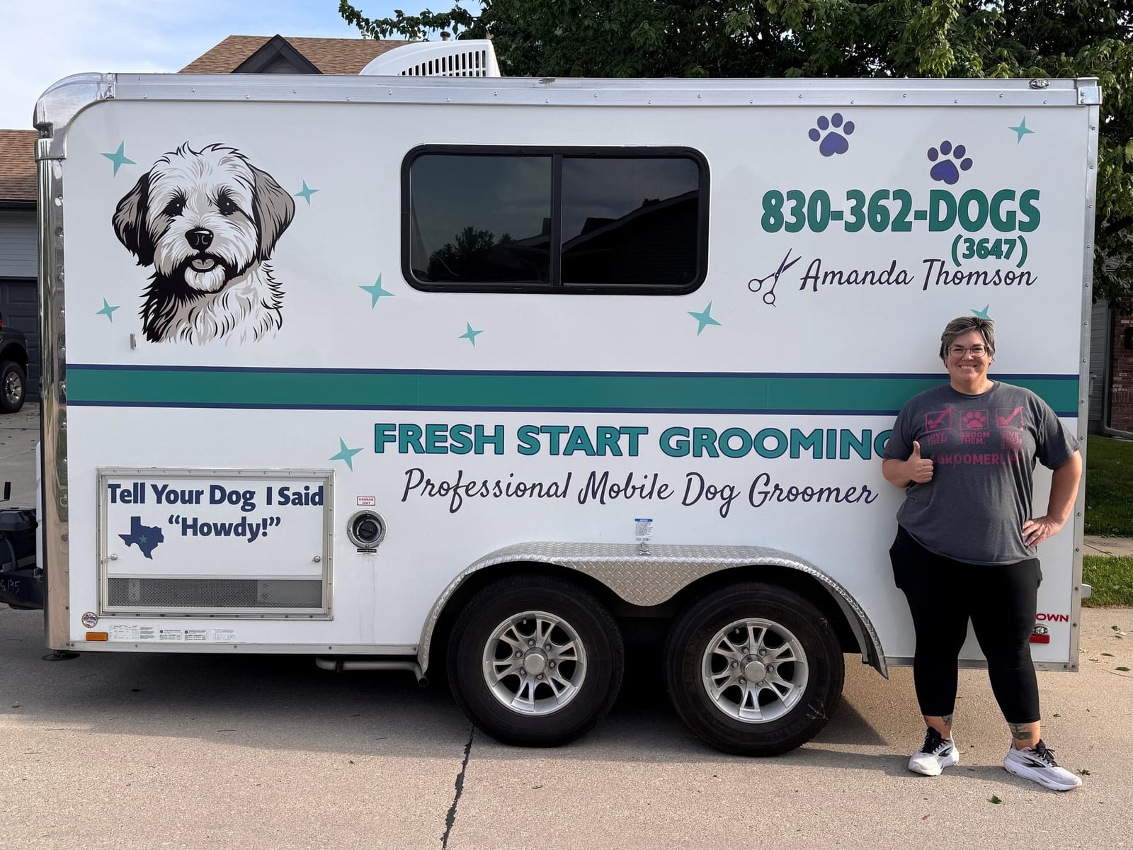 Amanda Thomson giving a thumbs up next to her Fresh Start Grooming trailer, wrapped in the teal and plum brand the new website was built from